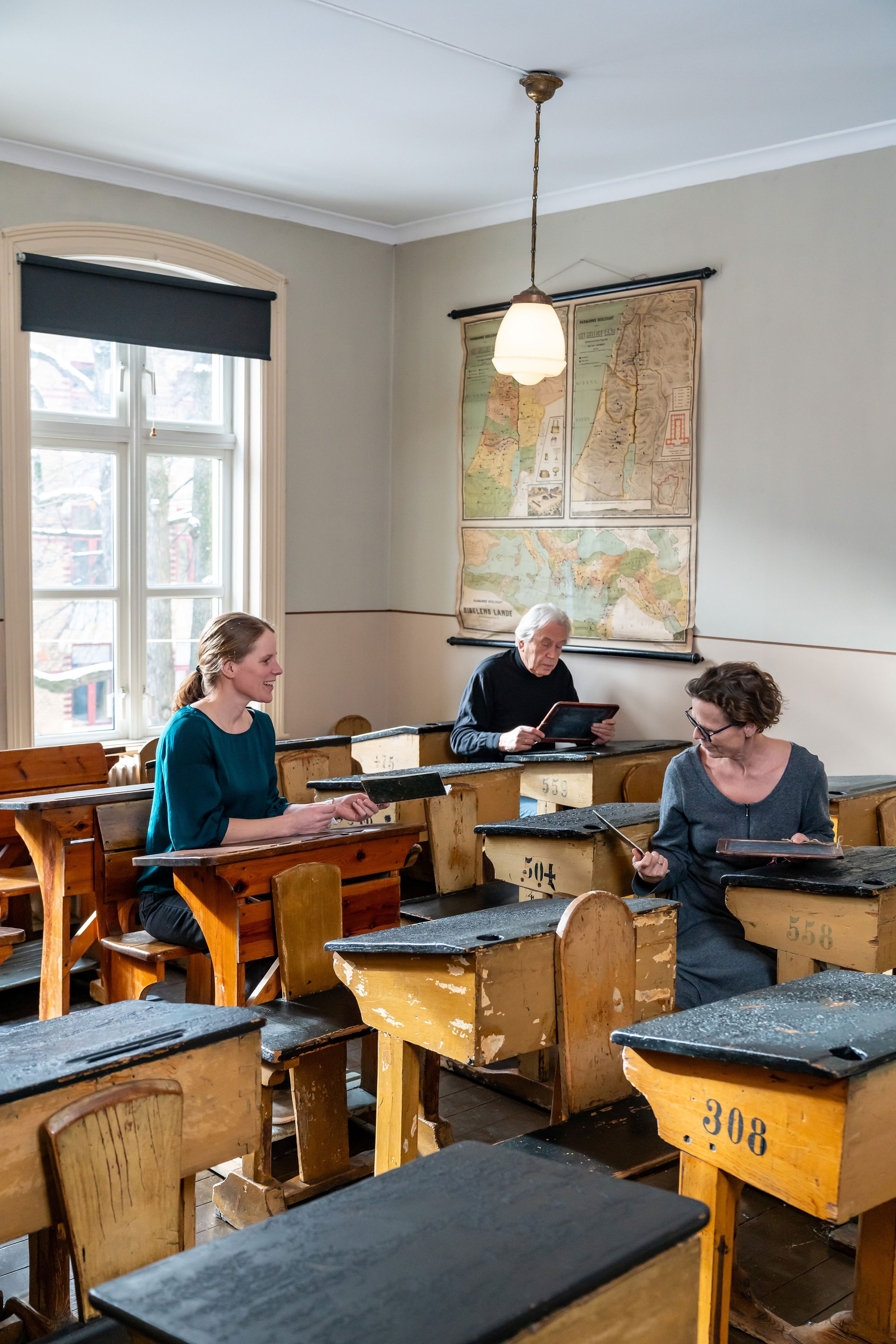 en gruppe mennesker som sitter ved pulter i et rom